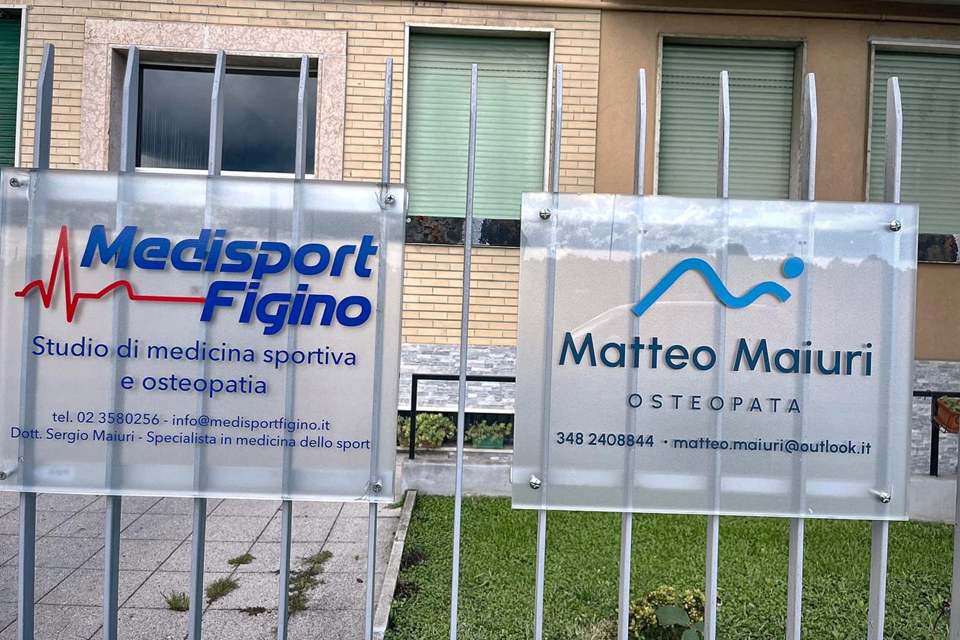 Le insegne di Medisport Figino e di Matteo Maiuri osteopata sulla cancellata di via Anghileri 4
