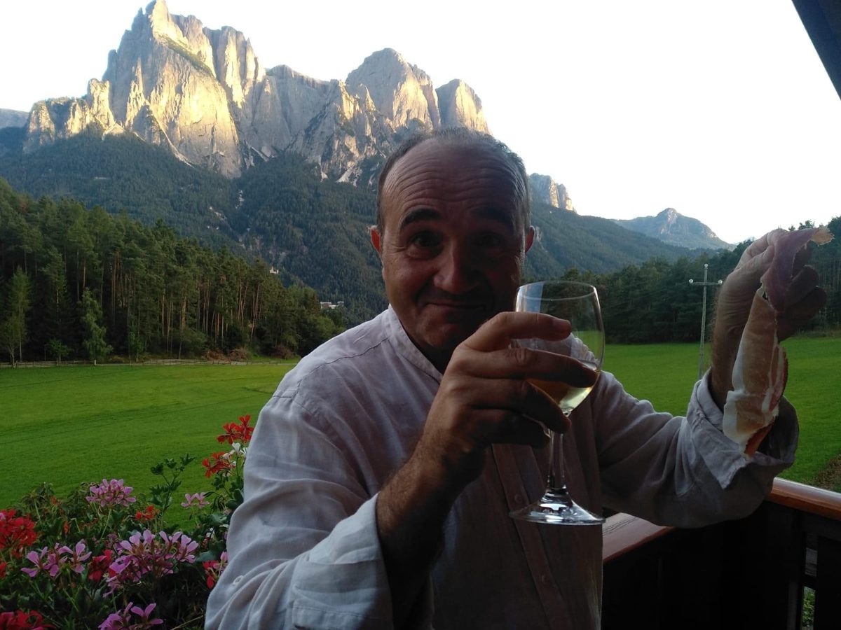 Il dott. Sergio Maiuri brinda con un calice di vino davanti alle Dolomiti