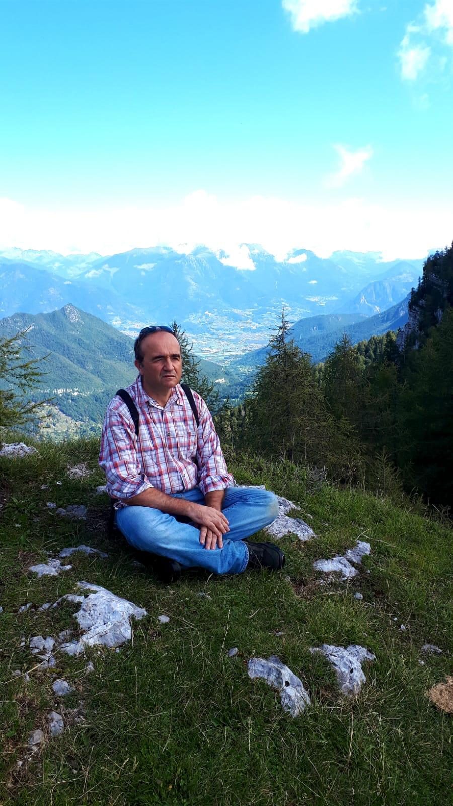 Il dott. Sergio Maiuri seduto sull'erba durante un'escursione in montagna