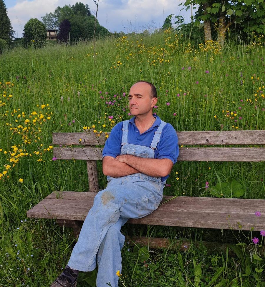 Il dott. Sergio Maiuri seduto su una panchina in un prato fiorito